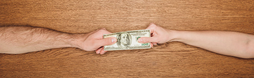 Two hands and arms pulling at American $100 bill - the fight over unclaimed property continues in October 2019